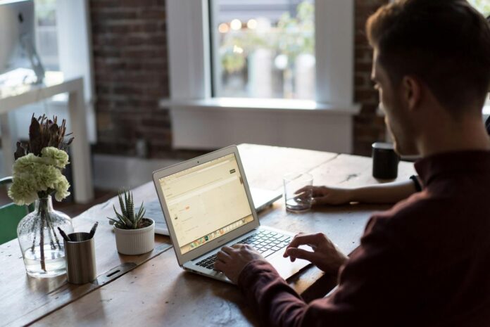 Pria mengoperasikan laptop di atas meja