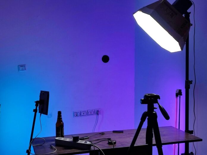 Pengaturan studio dengan lampu, kamera, dan meja.